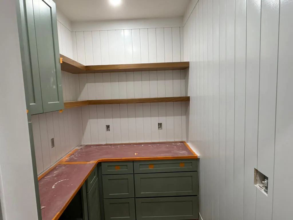 Mudroom with green cabinets and wood shelves
